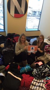Northwestern College's Lauren Schumacher (left) and Brenda Christy revel amidst the coats, hats, gloves, etc. collected during its One Warm Coat® Drive, which will benefit Cornerstone Community Outreach in Chicago.