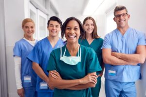 Group of five smiling medical professionals wearing scrubs